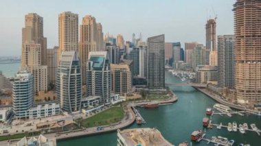 Panorama, Dubai Marina 'yı limana park etmiş birkaç tekne ve yatla ve kanalın çevresindeki gökdelenlerle gösteriyor. Arka planda JBR bölgesi kuleleri