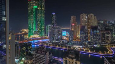 Panorama, Dubai Marina gökdelenlerini ve JBR bölgesini lüks binalar ve dinlenme yerleri ile gösteriyor. Aydınlatılmış rıhtım ve kanalda yüzen tekneler