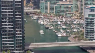 Birçok yat ve tekne, gölgeler hızla ilerlerken bütün gün boyunca limandaki hava saatlerinde park halindedir. Dubai Marina rıhtımı yürüyüş alanı. Modern tekne derede yüzüyor..