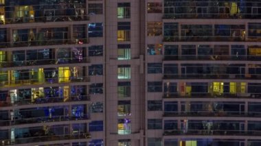 Dışarıdaki apartmanın gece manzarası renkli zaman çizelgesi. Pencere ve balkonlarında parlayan ışıklar olan yüksek gökdelen