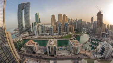 Dubai Marina Panorama 'sında limana park etmiş tekne ve yatlar ve kanalın çevresindeki gökdelenler gün doğumunda havalanacak. Arka planda JBR bölgesi kuleleri