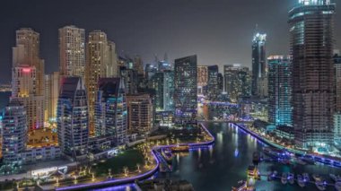 Panorama, Dubai Marina 'yı limana park etmiş birkaç tekne ve yatla gösteriyor. Kanal havası çevresindeki gökdelenleri aydınlatıyor. Arka planda JBR bölgesi kuleleri