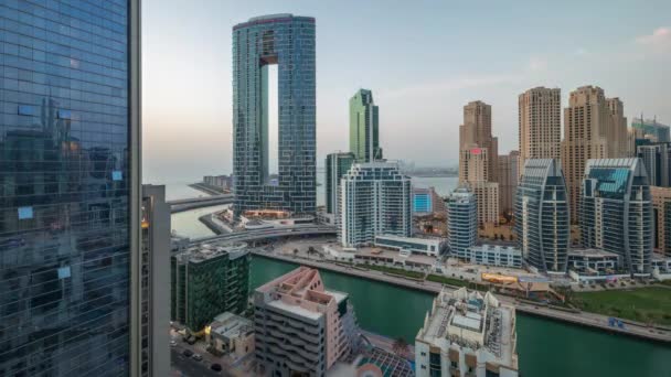 迪拜的滨海摩天大楼和Jbr区在日落后被照亮的豪华建筑和度假胜地从天而降的过渡时间 有手掌和小船漂浮在运河中 — 图库视频影像