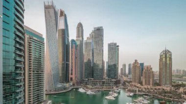 Dubai marinası en uzun gökdelenler ve yatlar liman havasından geceye geçiş günbatımından sonra panoramik zaman dilimi. Apartman binaları, oteller ve ofis blokları, modern konutlar