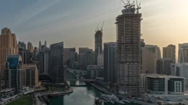 Panorama, Dubai Marina 'yı limana parkedilmiş tekne ve yatlarla ve kanalın çevresindeki gökdelenlerle gün doğumunda hava durumunu gösteriyor. Arka planda JBR bölgesi kuleleri