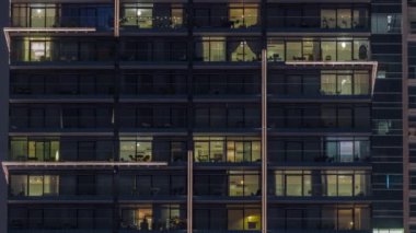 Çok katlı binaların panoramik pencerelerinde, çok renkli ışıktan oluşan düz bir panorama. Büyük bir şehirde aydınlık bir gökdelen.