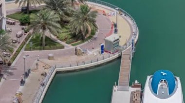 İnşaatçılar, Dubai Marina 'da su nakliye istasyonunun yakınlarındaki palmiyelerle rıhtımın yeniden inşasını yapıyorlar. Yeni sarı tuğlalı fayanslar kaldırımda. Yatlar ve tekneler yüzüyor