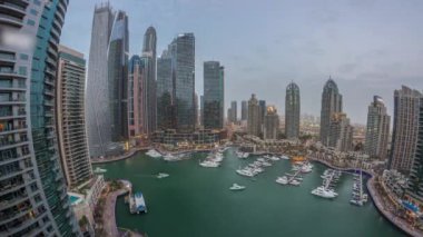 Dubai marinası en uzun gökdelenler panorama ve liman havasında yatlar gün batımından sonra gece geçiş zamanı. Apartman binaları, oteller ve ofis blokları, modern konutlar
