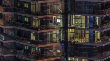 Çok katlı binaların pencerelerinde, çok renkli ışıktan oluşan düz bir panorama. Büyük bir şehirde yansımalarla aydınlatılmış gökdelen.