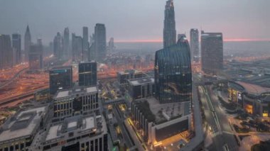 Fütürist Dubai Şehir Merkezi ve finans bölgesi gökyüzü gece gündüz geçiş zamanı. Birçok aydınlık kule ve gökdelenler güneş doğmadan önce sabah sisi ile