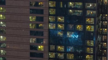 Panoramik pencerelerin dışında gece vakti üst sınıf bir binanın apartmanında. Gökdelende parlayan ışıklar