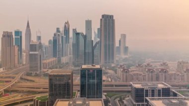 Dubai Finans Merkezi 'nin Panorama' sında uzun gökdelenler zaman ayarlı. Gün doğmadan önce sabah sisi olan işlek otoyol boyunca bulunan kulelerin hava görüntüsü