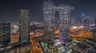 Panorama fütüristik Dubai şehir merkezi ve finans bölgesi gökyüzü gece zaman çizelgesini gösteriyor. Birçok aydınlık kule ve gökdelenler caddelerde trafik var.