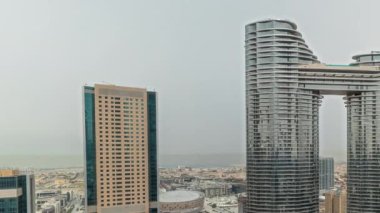 Pnorama, fütüristik Dubai şehir merkezi ve finans bölgesinin ufuk çizgisi zaman çizelgesini gösteriyor. Caddelerde trafik olan birçok kule ve gökdelenler. Arka planda şehir yürüyüş bölgesi