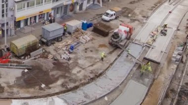 Beton yol yapımında çok sayıda işçi ve mikser makinesi, vinç, traktör zaman ayarlı çalışır. Tramvay raylarının yeniden inşası. Bulutlu bir günde hava üst görünümü