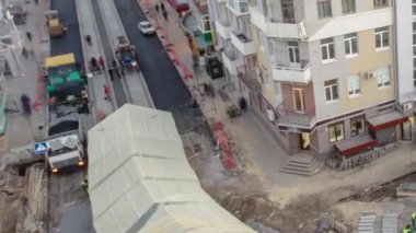 Asfalt kaldırım taşı, paten ve kamyon asfaltlama sırasında yol onarım alanında. Çadırın altındaki tramvay raylarının havadan görünüşü. Yol yapım ekipmanları. İnşaat işçileri yolda.