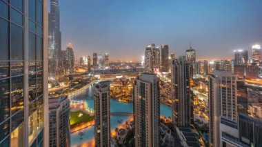 Dubai şehir merkezinde fıskiyeler ve modern fütüristik mimari gece gündüz geçiş zamanlarıyla gün doğumundan önce. Eski şehir ve alışveriş merkezi olan gökdelenlere panoramik manzara