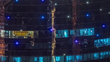 Modern kuledeki ofis pencereleri gece saatlerinde yanıp sönüyor. İçinde aydınlık odalar olan çok katlı gökdelenler..
