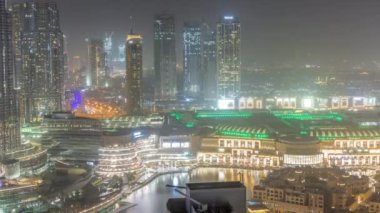 Dubai şehir merkezinde gece boyunca fıskiyeler ve modern mimari antenlerle. Alışveriş merkezli inşaat halindeki gökdelenlere bakın. Işıklar kapanıyor.
