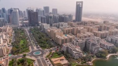 Barsha Heights bölgesindeki gökdelenler ve Greenens bölgesindeki alçak binalar. Dubai silueti tüm gün boyunca gölgeler hızla ilerlerken. Sokaklarda palmiyeler ve ağaçlar