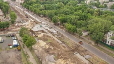 Buldozer panoramik hava görüntüsü, sanayi kamyonu kazıcı zemin hareket ediyor ve yol inşaatındaki bir çöp kamyonuna yükleniyor. Tramvay raylarının yeniden inşası
