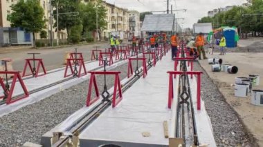 Kurulum aşamasındaki tramvay rayları ve zaman dilimindeki beton plakalara entegrasyon. İşçiler, demiryolu konfor sistemi için anti-titreşim reçinesi koyuyorlar. İşlem...
