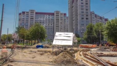 Sarı inşaat teleskopik vinç hareket halindeki tramvay rayları zaman ayarlı. Şapkalı ve üniformalı endüstriyel işçiler. Şehir caddesindeki tramvay raylarının yeniden inşası. Arka plandaki evler