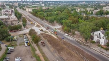 Büyük inşaat alanının panoramik hava görüntüsü. Buldozer, endüstriyel kamyon kazıcısı toprağı hareket ettiriyor ve bir çöp kamyonuna yüklüyor. Tramvay raylarının yeniden inşası