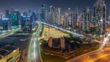 Bay Bulvarı 'nda aydınlatmalı modern kuleler Business Bay havacılık panoramiklerinde yerleşim alanları var. Tüm gece boyunca zaman çizelgesi, Dubai, BAE. Büyük otoparkın yakınında ışıkları kapanan gökdelenler.