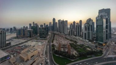 Bay Bulvarı 'nın Panorama' sı, Business Bay hava sahasında modern kuleler, gündüz, gece geçiş zamanı, Dubai, BAE. Büyük otoparkın yakınındaki yolda trafiği olan gökdelenler.