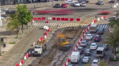 Endüstriyel kamyon yükleyicisi toprağı taşıyor ve eski demiryolu uyuyanlarını yol inşaatındaki bir çöp kamyonuna yüklüyor. Kavşaktaki tramvay raylarının hava görüntüsü