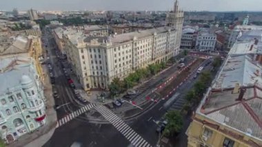 Ukrayna 'nın Kharkiv kentinde tarihi binalar bulunan Anayasa Meydanı manzarası. Yol kavşağında trafik vardı ve evin yakınındaki inşaat alanında da bir kule vardı. Çatıdan görüntüle