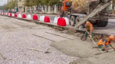 Turuncu üniformalı ve mikser makineli işçilerle yol inşaatı için beton döşeme ve seviyelendirme. Tramvay raylarının yeniden inşası
