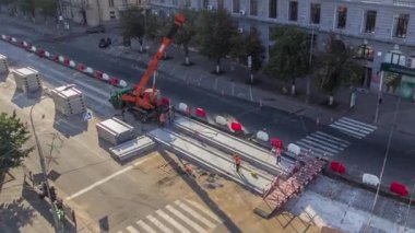 Yol inşaatı zamanına vinçle beton plakalar yerleştiriliyor. Şapkalı ve üniformalı endüstriyel işçiler. Havadan panoramik üst görüntü. Şehir caddesindeki tramvay raylarının yeniden inşası