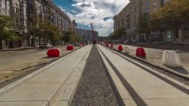 Yol inşaatı zamanına vinçle beton plakalar yerleştiriliyor. Şehir merkezinde yoğun sokak trafiği var. Şehir caddesindeki tramvay raylarının yeniden inşası