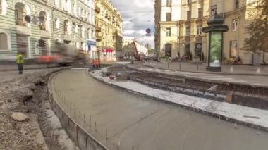 Beton, turuncu üniformalı ve mikser makineli işçilerle yol inşaatı için şehir caddesinde çalışıyor. Tramvay raylarının yeniden inşası