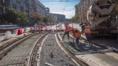 Beton döşeme ve karayolu inşaatı. Turuncu üniformalı birçok işçi ve şehir trafiği. Tramvay raylarının yeniden inşası