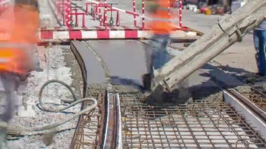 Beton, turuncu üniformalı ve mikser makineli işçilerle bir şehir merkezinde yol inşaatında çalışıyor. Tramvay raylarının yeniden inşası