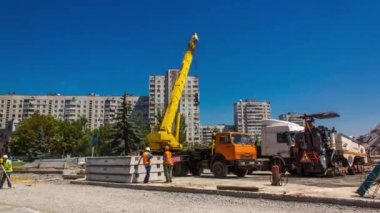 Yol inşaatı zamanında vinçle beton plakalar boşaltılıyor. Şapkalı ve üniformalı endüstriyel işçiler. Şehir caddesindeki tramvay raylarının yeniden inşası