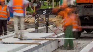 Yol inşaatı zamanına vinçle beton plakalar yerleştiriliyor. Arka planda inşaat halindeki bir ev. Şapkalı ve üniformalı endüstriyel işçiler. Tramvay raylarının yeniden inşası