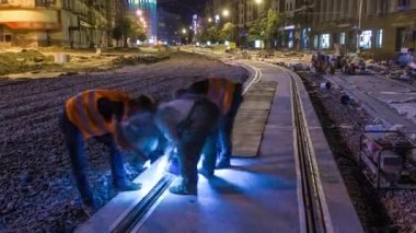 Tram rails at the final stage of their installation and integration into concrete plates on the road night timelapse in the city. Filling by liquid resin for reduction of vibration and noice. The