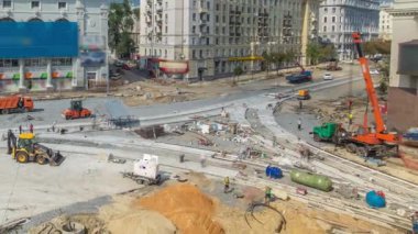 Road construction site with concrete works for road construction with many workers in uniform and many machines with trucks and bulldozers panoramic aerial timelapse. Reconstruction of tram tracks
