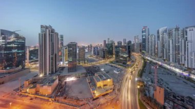 Business Bay hava sahasında modern kuleleri olan Bay Bulvarı gece gündüz panoramik geçiş zamanı, Dubai, BAE. Yol ve inşaat alanında trafiği olan gökdelenler