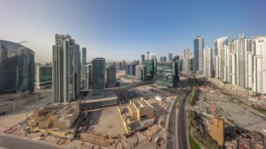 Gündoğumu sırasında Business Bay havacılık panoramik zaman diliminde modern kuleleri olan Bay Avenue, Dubai, BAE. Büyük otoparkın yakınındaki yolda trafiği olan gökdelenler.