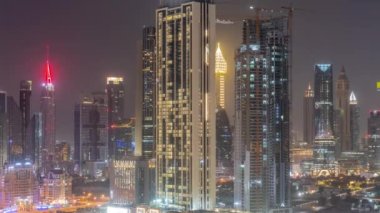 Dubai, BAE 'de tüm gece boyunca Sheikh Zayed Yolu ve DIFC bölge anteninin etrafındaki yüksek binaların sıraları. Uluslararası Finans Merkezi gökdelenleri ve ışıkları sönük