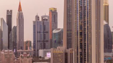 Sheikh Zayed Yolu ve DIFC bölgesi çevresindeki yüksek binalar ve Dubai, BAE 'deki gece gündüz geçiş zamanları. Cam yüzeyi olan Uluslararası Finans Merkezi gökdelenleri