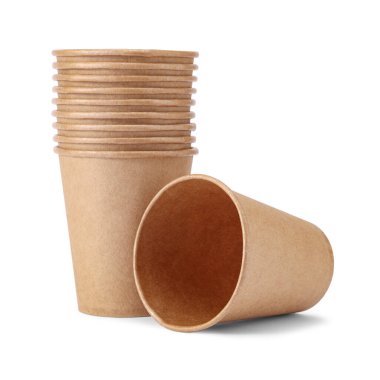 Tek kullanımlık kağıt bardak, beyaz arka planda izole edilmiş bir yığın fincanın yanında duruyor. Doğal malzemeden çevre dostu tek kullanımlık sofra takımı.