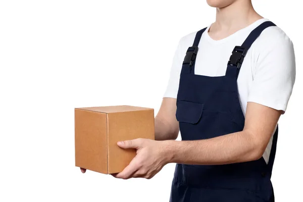 Adamın bedeni önünde bir karton kutu tutuyor ve beyaz arka planda izole bir şekilde teslim ediyor. Koyu mavi tulumlu ve beyaz tişörtlü bir adam. Teslimat konsepti.