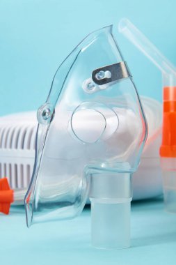 Mavi arkaplandaki kompresör nebulizörü için solunum maskesini kapatın. Astım ve solunum hastalıkları için solunum terapisi için tıbbi ekipman..