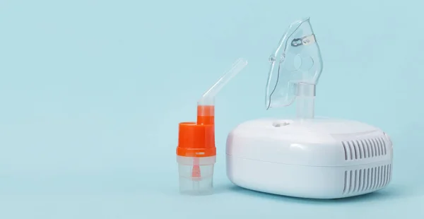 Solunum maskesi ve mavi zemin üzerinde kompresör spreyi için nebulizer ağızlıklı atomlaştırma bardağı, solda boş yer. Astım ve solunum hastalıkları için solunum terapisi için tıbbi ekipman..